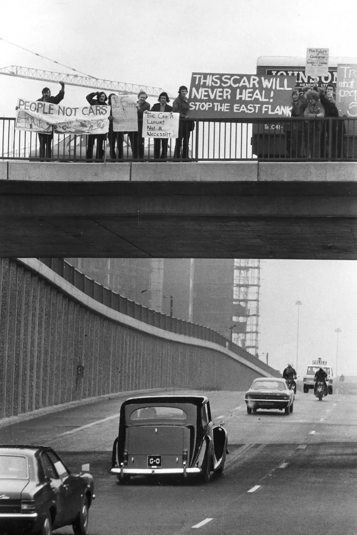 Historic protest against the M8 motorway construction in Glasgow, showing residents holding a banner reading 'This scar will never heal'